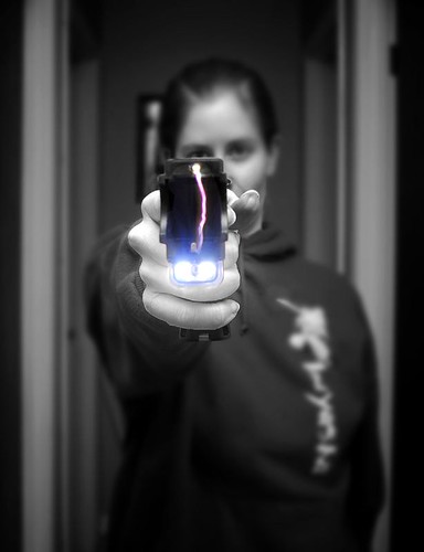 Tjej med elchockvapen. Bild: "Taser tester" by J. Star is licensed under CC BY-NC-SA 2.0.
